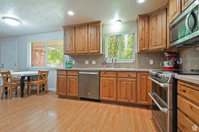 628 E Wyandotte Ave S, Sandy, UT 84070 - kitchen featuring stainless steel appliances, light wood-style flooring, a sink, backsplash, and a textured ceiling