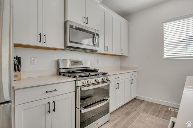 1053 E Preston Ave, Layton, UT 84040 - kitchen featuring appliances with stainless steel finishes, light wood-type flooring, light countertops, white cabinetry, and baseboards