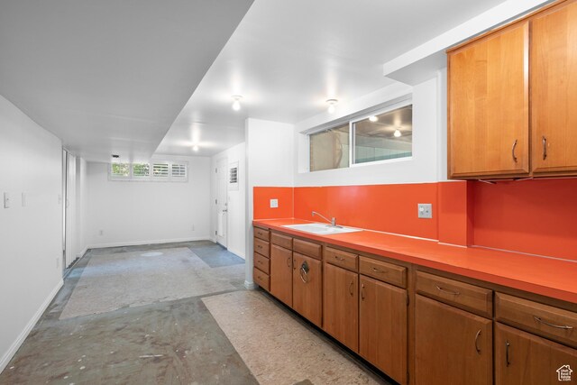 3243 S 200 W, Bountiful, UT 84010 - kitchen with a sink, baseboards, light countertops, unfinished concrete floors, and brown cabinetry