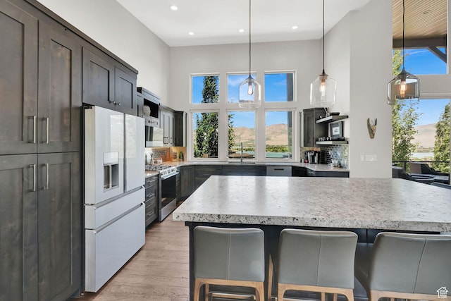 6339 E Quail Ln, Huntsville, UT 84317 - kitchen with white refrigerator with ice dispenser, stainless steel range with gas stovetop, a sink, a kitchen bar, and light wood-type flooring
