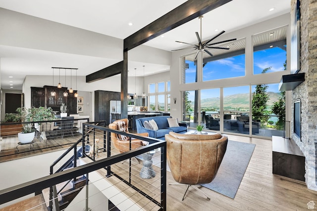 6339 E Quail Ln, Huntsville, UT 84317 - living area featuring beamed ceiling, a fireplace, a ceiling fan, a high ceiling, and light wood-style floors