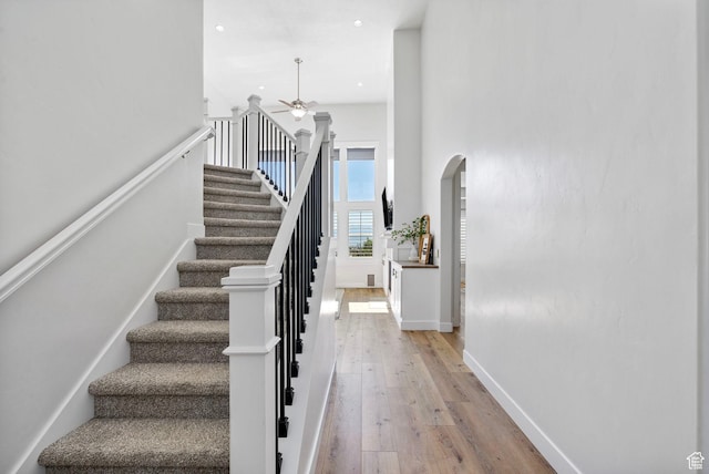 722 N Meridian Dr, Saratoga Springs, UT 84045 - staircase with arched walkways, a ceiling fan, wood finished floors, a towering ceiling, and recessed lighting