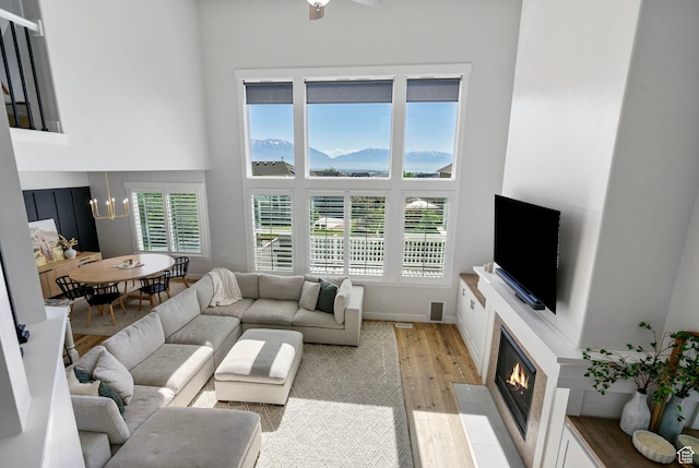 722 N Meridian Dr, Saratoga Springs, UT 84045 - living area with a high ceiling, light wood-type flooring, a fireplace with flush hearth, plenty of natural light, and a chandelier