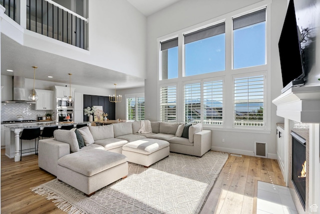 722 N Meridian Dr, Saratoga Springs, UT 84045 - living area featuring light wood-type flooring, a fireplace, a chandelier, baseboards, and a high ceiling