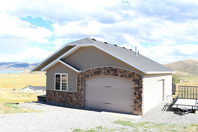 45 Wedge Way, Garden City, UT 84028 - view of front of house featuring stone siding, a mountain view, an attached garage, and gravel driveway