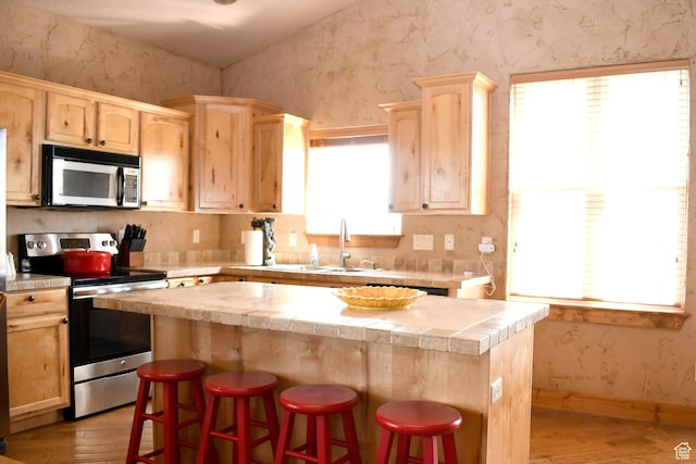 45 Wedge Way, Garden City, UT 84028 - kitchen featuring appliances with stainless steel finishes, light brown cabinetry, light wood-type flooring, a center island, and light countertops