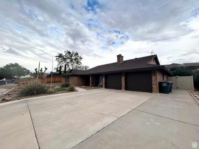 344 E Vermillion Ave, St George, UT 84790 - view of front of home featuring an attached garage, driveway, brick siding, a gate, and a chimney