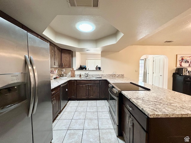 344 E Vermillion Ave, St George, UT 84790 - kitchen with appliances with stainless steel finishes, a peninsula, dark brown cabinets, and a tray ceiling