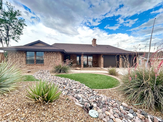 344 E Vermillion Ave, St George, UT 84790 - rear view of house with brick siding, an attached garage, a chimney, roof with shingles, and a lawn