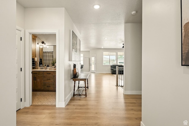 4657 W 275 N, Cedar City, UT 84720 - corridor featuring light wood-style floors, a textured ceiling, baseboards, a sink, and recessed lighting