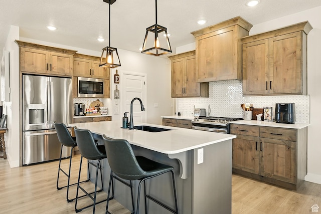 4657 W 275 N, Cedar City, UT 84720 - kitchen with appliances with stainless steel finishes, a sink, light wood-type flooring, tasteful backsplash, and an island with sink