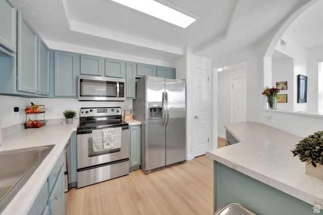 14284 S Daisyfield Dr E, Draper, UT 84020 - kitchen featuring stainless steel appliances, light wood-style flooring, a sink, arched walkways, and light countertops