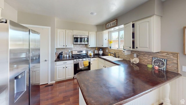 540 E 990 N, Pleasant Grove, UT 84062 - kitchen featuring appliances with stainless steel finishes, a sink, dark countertops, a peninsula, and dark wood-type flooring