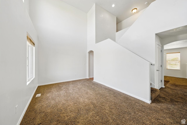13708 S Manas Ct, Herriman, UT 84096 - empty room featuring arched walkways, carpet, a towering ceiling, and baseboards