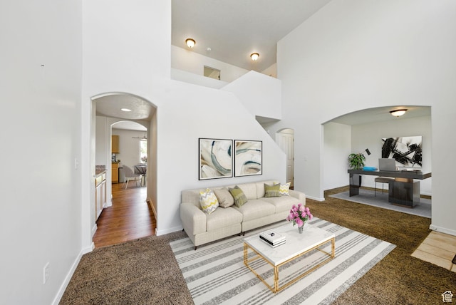 13708 S Manas Ct, Herriman, UT 84096 - living room with arched walkways, carpet floors, a towering ceiling, and baseboards