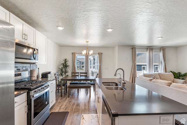 3970 W Cool Spring Ave, Lehi, UT 84043 - kitchen with stainless steel appliances, dark countertops, a sink, an island with sink, and plenty of natural light