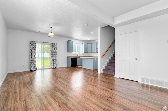 4699 W Greensand Dr S, West Jordan, UT 84084 - unfurnished living room featuring light wood-style flooring, stairway, baseboards, a textured ceiling, and recessed lighting
