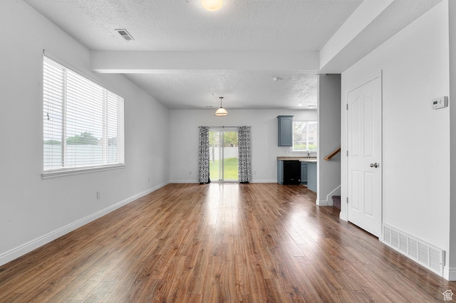 4699 W Greensand Dr S, West Jordan, UT 84084 - unfurnished living room with a textured ceiling, wood finished floors, baseboards, a sink, and stairway