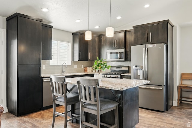 48 S Cimarron Cir, Cedar City, UT 84720 - kitchen featuring appliances with stainless steel finishes, a sink, tasteful backsplash, a kitchen island, and a breakfast bar area