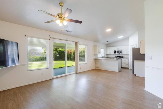 710 S Indian Hills Dr # 64, St George, UT 84770 - kitchen with a peninsula, lofted ceiling, stainless steel microwave, open floor plan, and light wood-style flooring