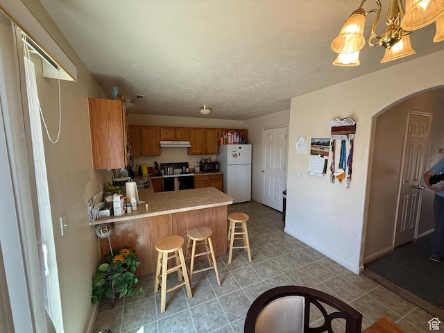 1087 N 1800th Cir W, St George, UT 84770 - kitchen with freestanding refrigerator, range with electric stovetop, a peninsula, brown cabinetry, and light countertops