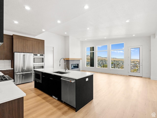 7272 W Summit Crest Cir, Herriman, UT 84096 - kitchen featuring appliances with stainless steel finishes, light wood-style flooring, a center island with sink, light countertops, and open floor plan