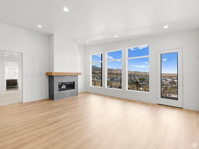 7272 W Summit Crest Cir, Herriman, UT 84096 - unfurnished living room with recessed lighting, a tile fireplace, and light wood-style flooring