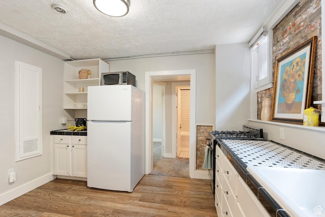 86 B St E Unit 24, Salt Lake City, UT 84150 - kitchen with freestanding refrigerator, tile countertops, stainless steel microwave, open shelves, and light wood-type flooring