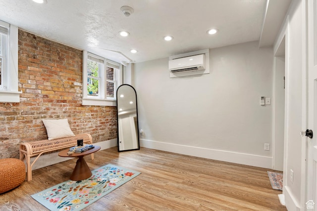 86 B St E Unit 24, Salt Lake City, UT 84150 - sitting room featuring a wall mounted air conditioner, baseboards, light wood-style floors, recessed lighting, and brick wall