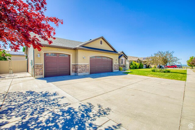 2155 N 170 W, Tooele, UT 84074 - view of front of home with stucco siding, concrete driveway, a garage, stone siding, and a gate