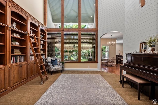 8149 S 2425 E, South Weber, UT 84405 - living area with a high ceiling, carpet, a chandelier, arched walkways, and wooden walls
