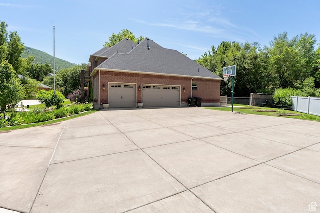 8149 S 2425 E, South Weber, UT 84405 - view of property exterior featuring an attached garage, brick siding, concrete driveway, roof with shingles, and a mountain view