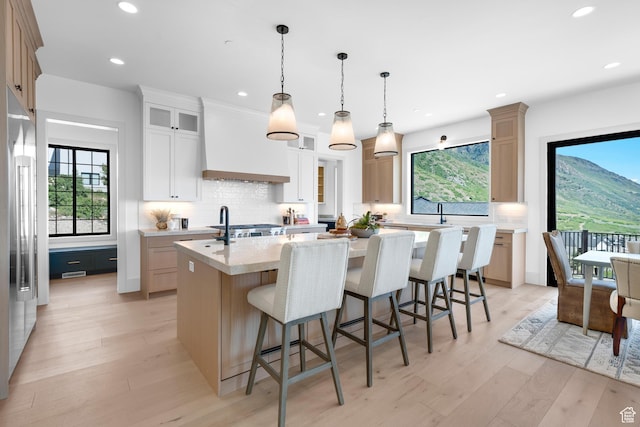 3851 W Box Elder Cir, Alpine, UT 84004 - kitchen featuring a kitchen island with sink, light wood-style flooring, premium range hood, tasteful backsplash, and recessed lighting