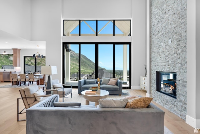 3851 W Box Elder Cir, Alpine, UT 84004 - living room with a towering ceiling, light wood-style flooring, a stone fireplace, a chandelier, and baseboards