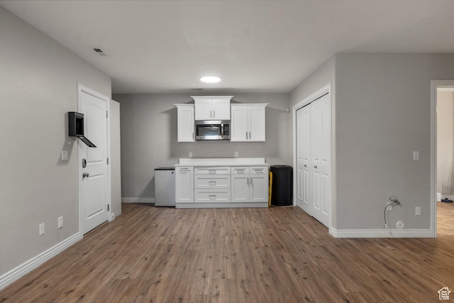 1754 E Cedar Trails Way, Eagle Mountain, UT 84005 - kitchen featuring stainless steel microwave, baseboards, wood finished floors, and white cabinetry