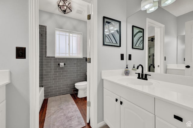4715 S 1500 E, Ogden, UT 84403 - full bath featuring vanity, toilet, wood finished floors, tile walls, and  shower combination