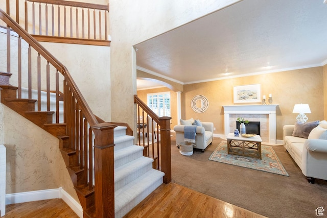 13279 S Berry Ln, Draper, UT 84020 - living room with arched walkways, wood finished floors, a tiled fireplace, stairway, and crown molding