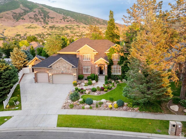 13279 S Berry Ln, Draper, UT 84020 - view of front of home with a garage, concrete driveway, a front lawn, a mountain view, and stone siding