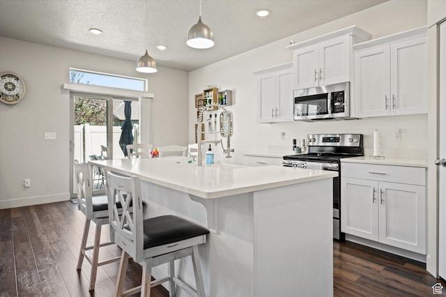 4488 S Haven Creek Rd W Unit 25D, West Haven, UT 84401 - kitchen featuring appliances with stainless steel finishes, dark wood-style floors, a kitchen bar, baseboards, and an island with sink