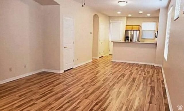 3400 E Hidden Springs Dr, Washington, UT 84780 - unfurnished living room featuring arched walkways, wood finished floors, and baseboards