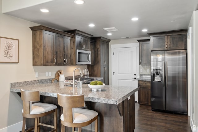 13609 N Hill Climb Ln, Kamas, UT 84036 - kitchen featuring stainless steel appliances, dark brown cabinets, a peninsula, dark wood finished floors, and a sink
