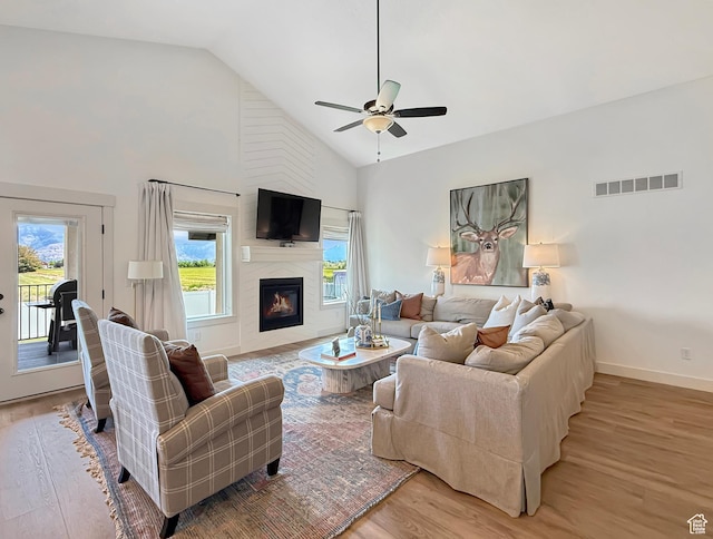 1852 N 4100 W, Plain City, UT 84404 - living room featuring light wood-style flooring, a ceiling fan, high vaulted ceiling, a large fireplace, and baseboards