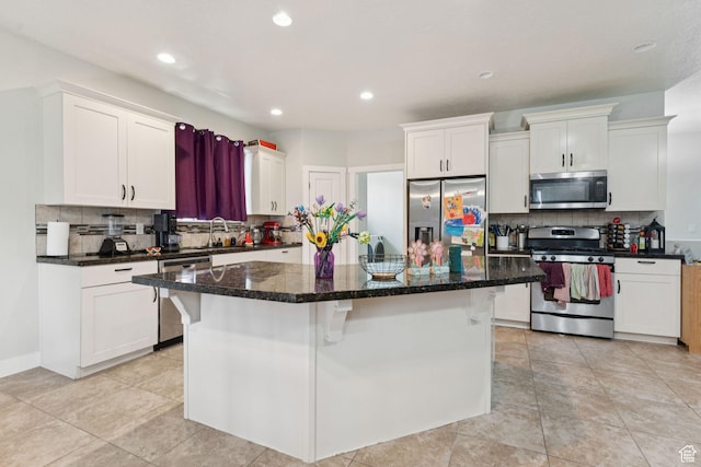 301 E Salem Park Cir, Salem, UT 84653 - kitchen with appliances with stainless steel finishes, backsplash, white cabinetry, a kitchen island, and a kitchen bar