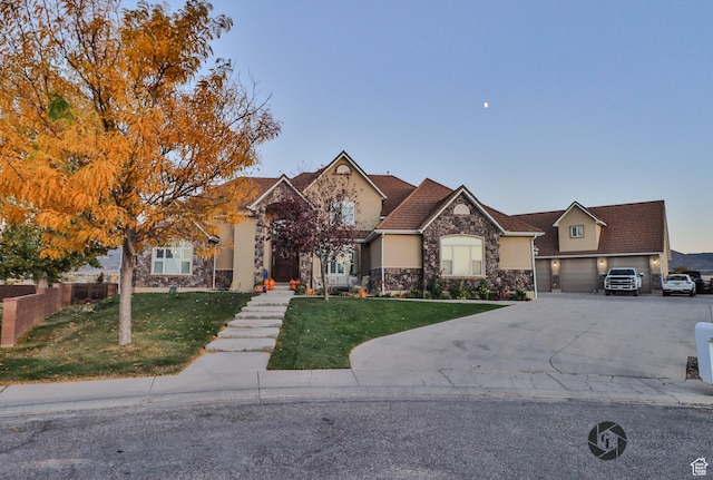 692 E 5020 N, Enoch, UT 84721 - view of front facade with stone siding, a front lawn, driveway, stucco siding, and a garage