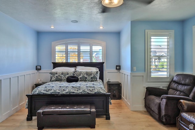 692 E 5020 N, Enoch, UT 84721 - bedroom with wainscoting, light wood finished floors, a decorative wall, and a textured ceiling