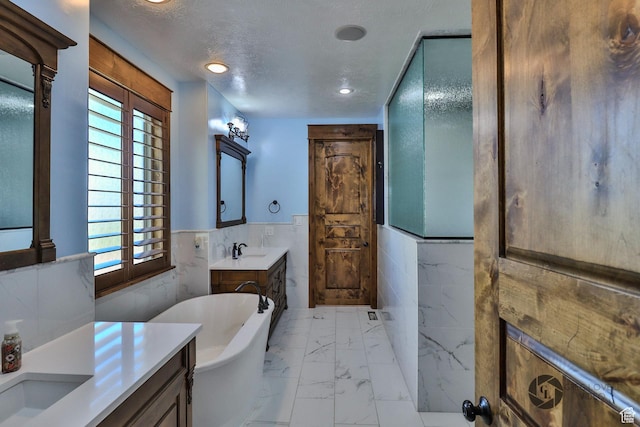 692 E 5020 N, Enoch, UT 84721 - bathroom featuring marble look tiles, vanity, a freestanding tub, tile walls, and wainscoting