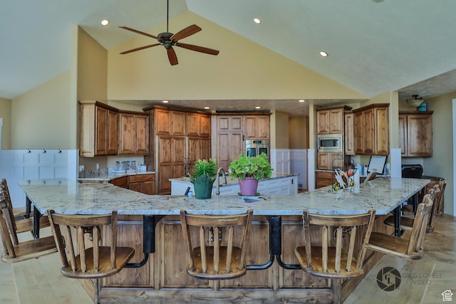 692 E 5020 N, Enoch, UT 84721 - kitchen with stainless steel appliances, high vaulted ceiling, ceiling fan, light stone countertops, and brown cabinetry