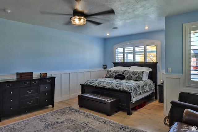 692 E 5020 N, Enoch, UT 84721 - bedroom featuring wainscoting, light wood finished floors, a ceiling fan, and a textured ceiling