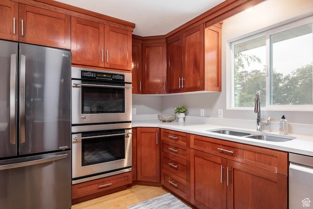 3427 S Fleetwood Dr, Salt Lake City, UT 84109 - kitchen featuring appliances with stainless steel finishes, a sink, light countertops, brown cabinetry, and light wood finished floors