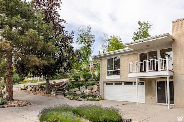 3427 S Fleetwood Dr, Salt Lake City, UT 84109 - view of side of property featuring a balcony, driveway, an attached garage, stairway, and brick siding